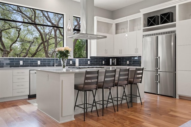 4907 Timberline Dr, Austin, TX 78746 - kitchen featuring stainless steel appliances, wall chimney exhaust hood, decorative backsplash, and a center island