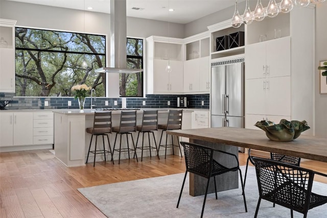 4907 Timberline Dr, Austin, TX 78746 - kitchen with stainless steel built in refrigerator, tasteful backsplash, white cabinetry, light wood finished floors, and recessed lighting