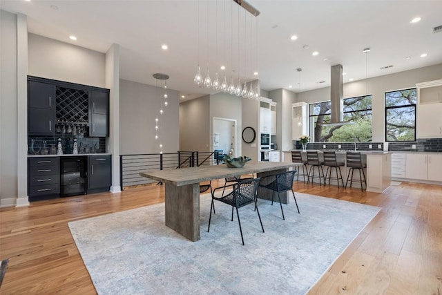 4907 Timberline Dr, Austin, TX 78746 - dining room featuring beverage cooler, a dry bar, light wood-style flooring, and recessed lighting