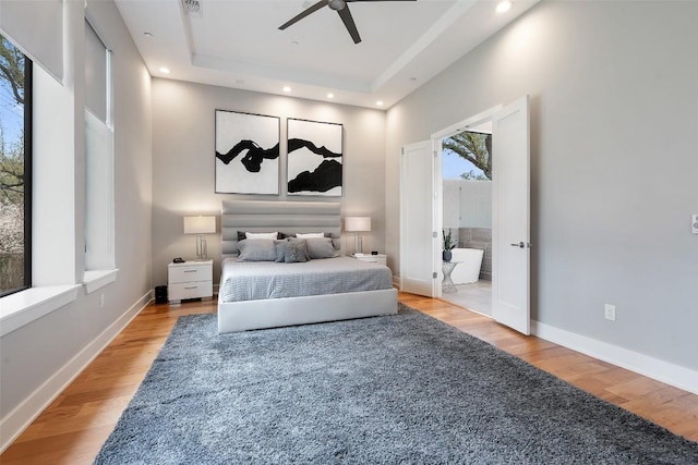4907 Timberline Dr, Austin, TX 78746 - bedroom featuring wood finished floors, a tray ceiling, recessed lighting, baseboards, and ensuite bath