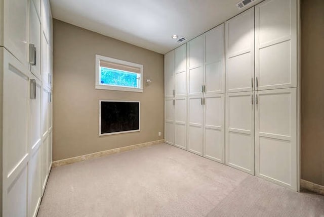 interior space with a closet, light colored carpet, visible vents, and baseboards