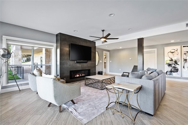 living room with ceiling fan, light wood finished floors, a fireplace, and baseboards