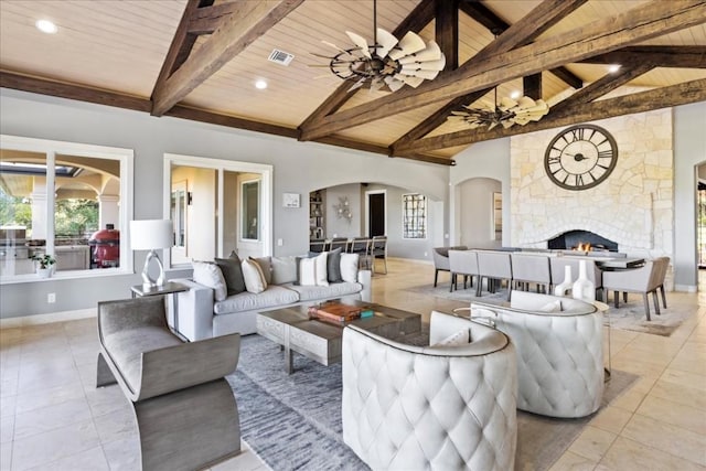 living room featuring a stone fireplace, wooden ceiling, visible vents, baseboards, and beamed ceiling