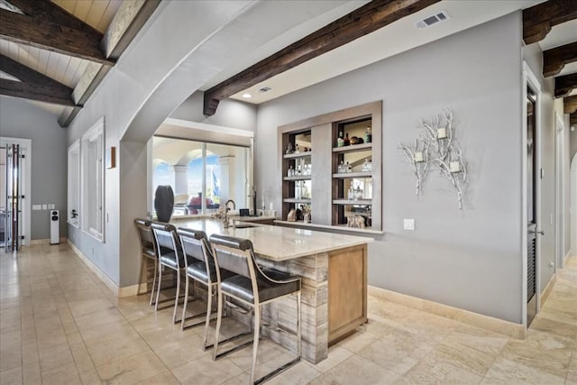 bar with lofted ceiling with beams, visible vents, baseboards, and a sink