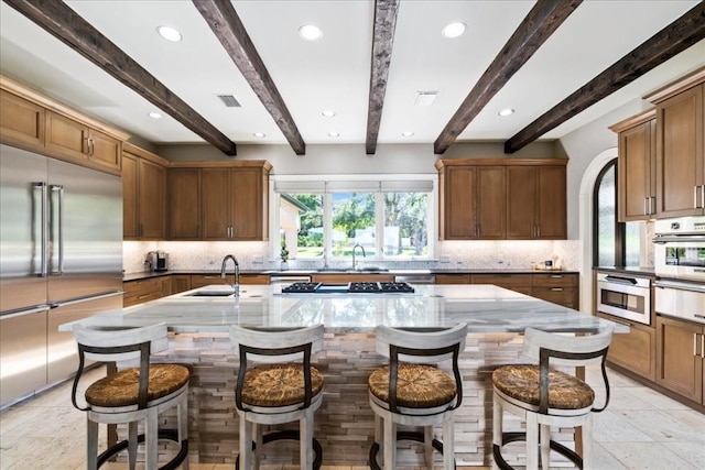 kitchen featuring an island with sink, appliances with stainless steel finishes, and a breakfast bar area