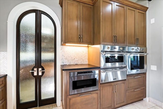 kitchen featuring a warming drawer, dark countertops, oven, and brown cabinets