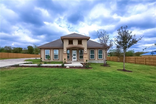 prairie-style home featuring fence private yard, roof with shingles, stucco siding, and a front yard