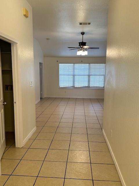 hallway with visible vents, baseboards, and light tile patterned floors