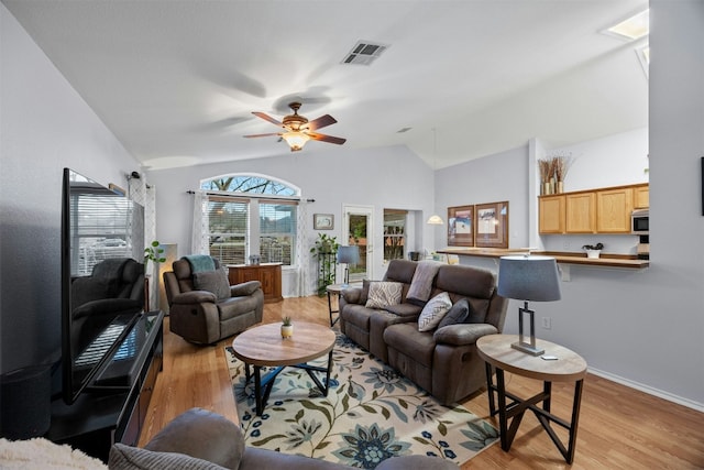 living room featuring vaulted ceiling, ceiling fan, visible vents, and light wood-style floors