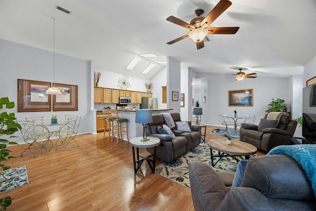 living area with lofted ceiling with skylight, light wood-style flooring, visible vents, and a ceiling fan