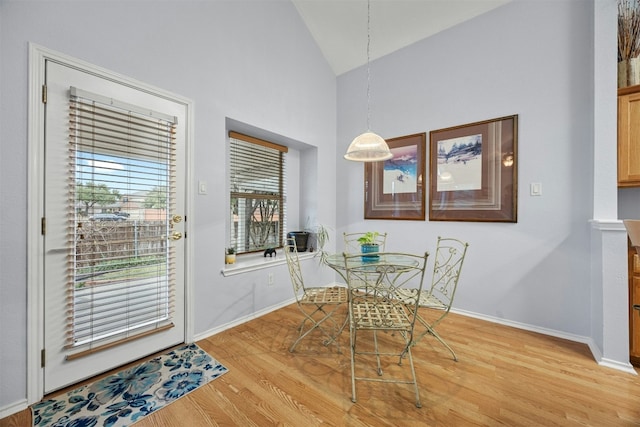 dining room with high vaulted ceiling, light wood-type flooring, and baseboards