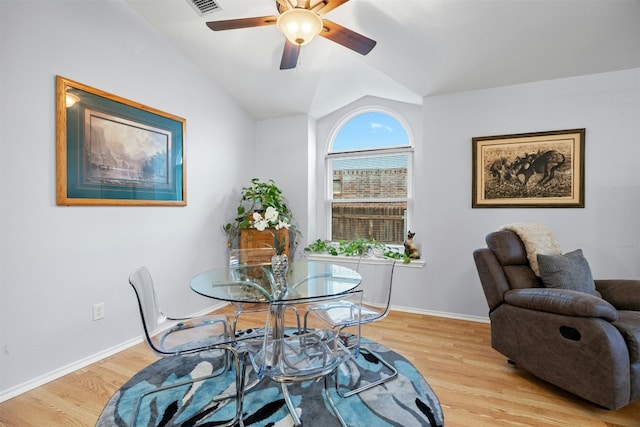 dining space featuring light wood-style flooring, baseboards, and vaulted ceiling