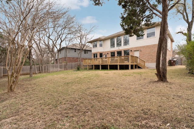 back of property with brick siding, a fenced backyard, a wooden deck, and a lawn