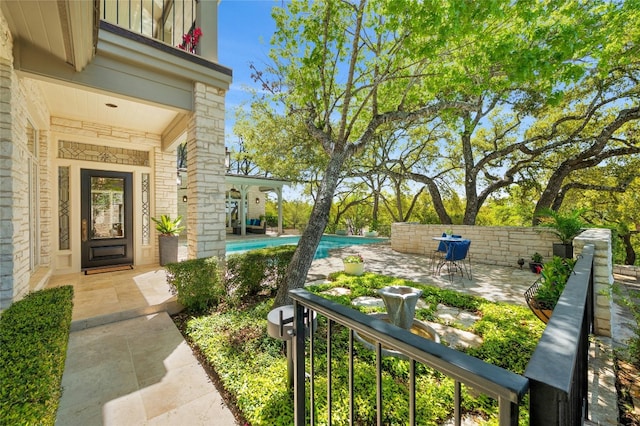 exterior space with stone siding, fence, a fenced in pool, and a patio