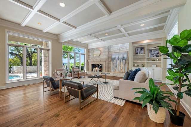 living room featuring a large fireplace, coffered ceiling, and wood finished floors