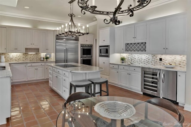 kitchen featuring beverage cooler, ornamental molding, built in appliances, white cabinetry, and backsplash