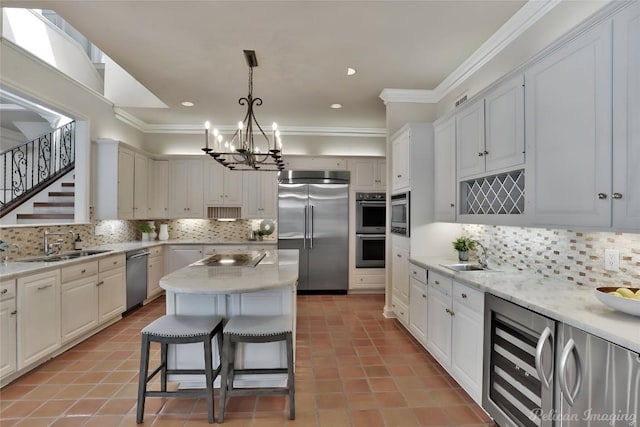 126 Firebird St, Lakeway, TX 78734 - kitchen with appliances with stainless steel finishes, beverage cooler, a chandelier, a sink, and crown molding
