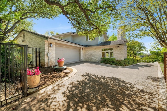 view of front of house featuring a garage, decorative driveway, and a chimney