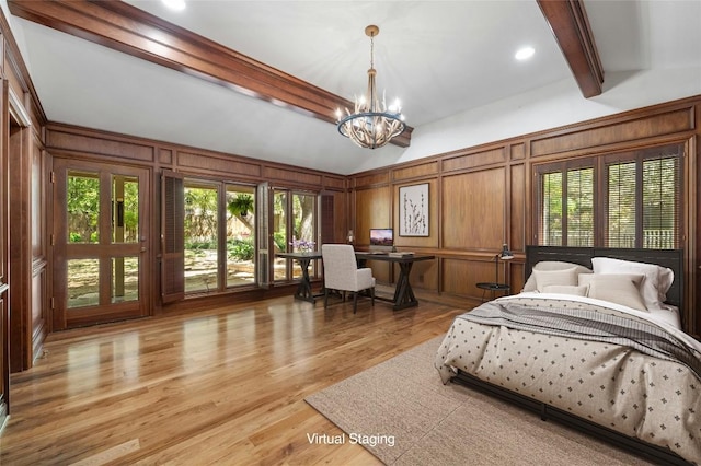 bedroom with multiple windows, a decorative wall, light wood-style flooring, and an inviting chandelier