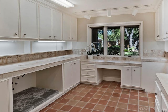 kitchen featuring light tile patterned floors, white cabinetry, light countertops, and built in desk