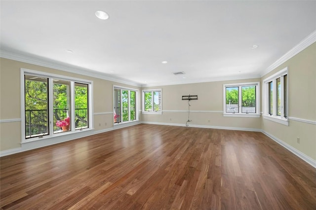 unfurnished living room featuring plenty of natural light, visible vents, wood finished floors, and ornamental molding