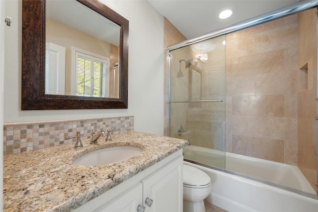 bathroom featuring toilet, shower / bath combination with glass door, decorative backsplash, and vanity