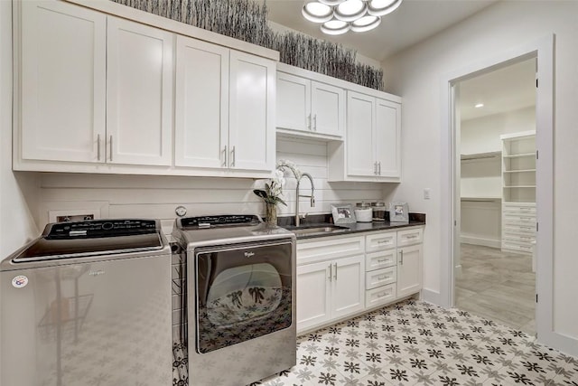 washroom featuring baseboards, a sink, cabinet space, and washer and dryer