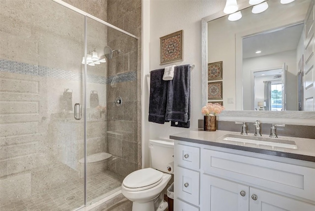 bathroom featuring toilet, a shower stall, and vanity