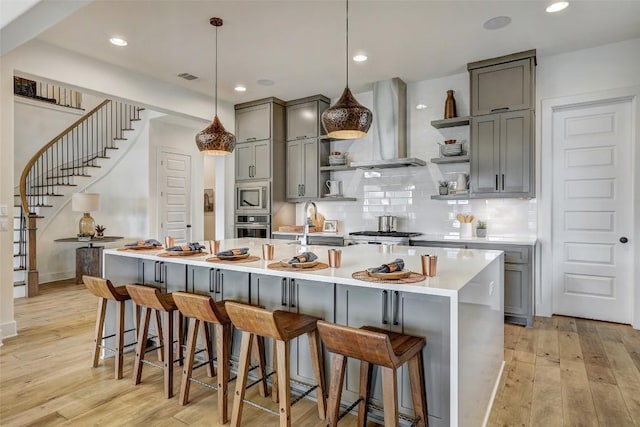 kitchen with extractor fan, a breakfast bar, hanging light fixtures, light countertops, and open shelves