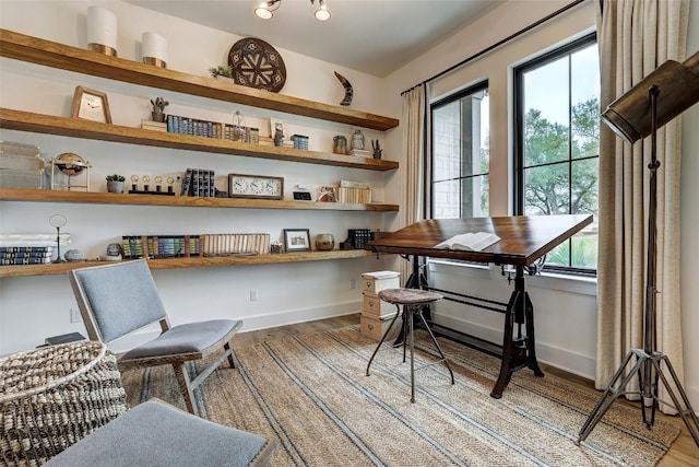 interior space featuring a healthy amount of sunlight, light wood-style floors, baseboards, and built in study area