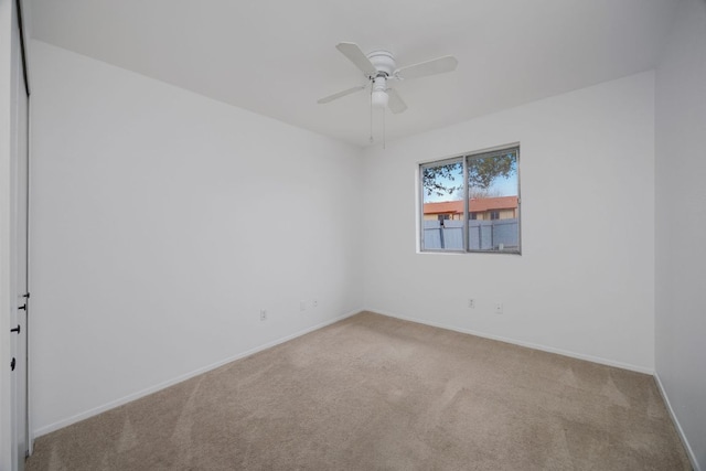 spare room with light carpet, ceiling fan, and baseboards