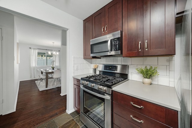 kitchen with stainless steel appliances, baseboards, light countertops, backsplash, and pendant lighting