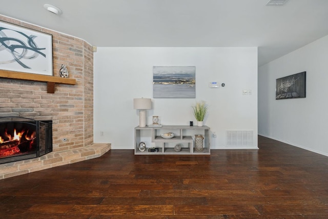 unfurnished living room with a fireplace, dark wood finished floors, visible vents, and baseboards