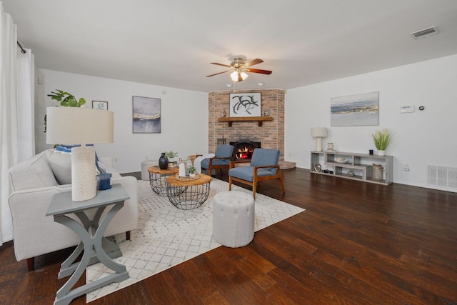 living room featuring ceiling fan, visible vents, a fireplace, and hardwood / wood-style flooring