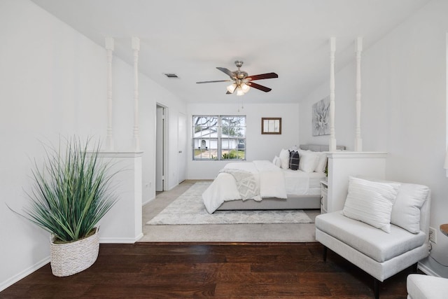 bedroom featuring a ceiling fan, visible vents, baseboards, and wood finished floors