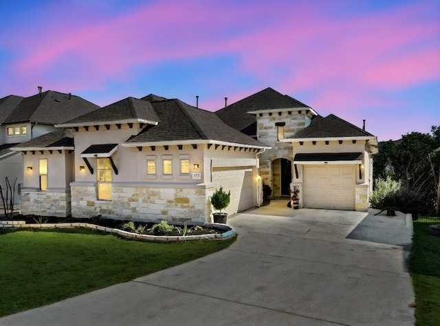 view of front facade with a yard, driveway, stone siding, and an attached garage