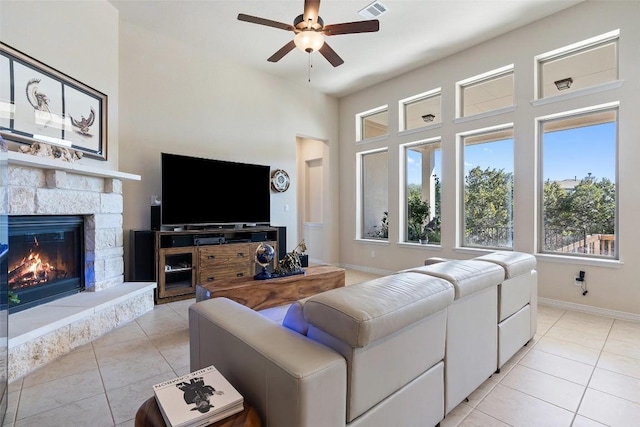 living room with light tile patterned floors, visible vents, baseboards, ceiling fan, and a fireplace