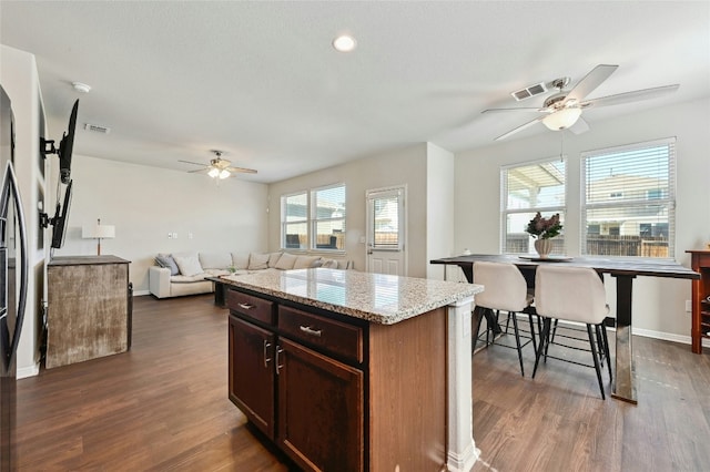 kitchen featuring a kitchen island, visible vents, open floor plan, and dark wood-type flooring