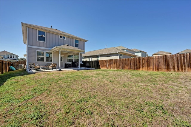 rear view of property featuring board and batten siding, a fenced backyard, a patio, and a lawn