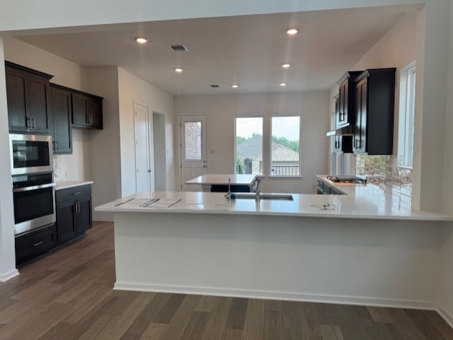 2705 Sage Ranch Dr Unit 24, Leander, TX 78641 - kitchen featuring stainless steel appliances, light countertops, dark wood-type flooring, a peninsula, and recessed lighting