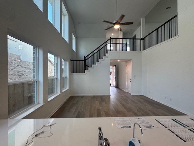 2705 Sage Ranch Dr Unit 24, Leander, TX 78641 - unfurnished living room with a high ceiling, healthy amount of natural light, wood finished floors, a ceiling fan, and stairs