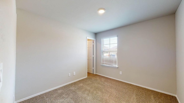 unfurnished room featuring light carpet and baseboards