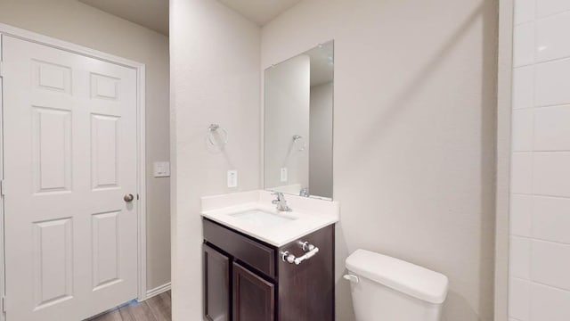 bathroom with toilet, wood finished floors, and vanity