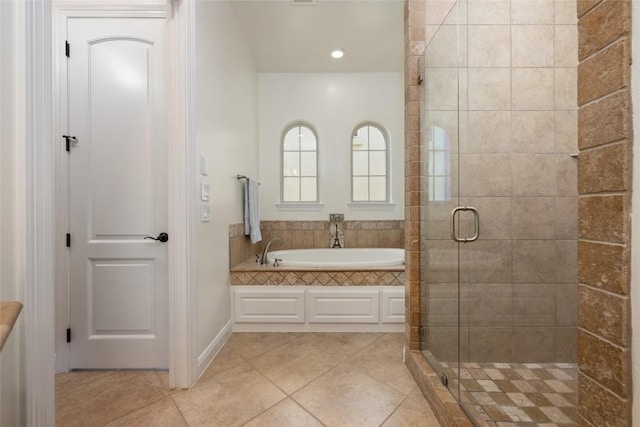 bathroom featuring a stall shower, tile patterned flooring, a garden tub, and baseboards