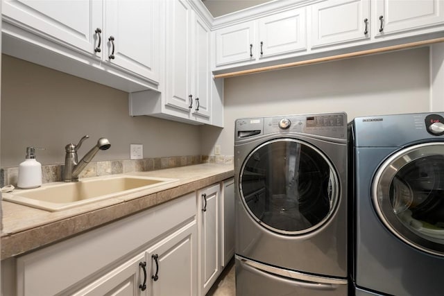 laundry area featuring washer and clothes dryer, a sink, and cabinet space