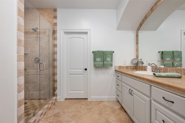 full bath with a shower stall, vanity, and baseboards