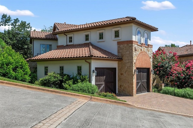 mediterranean / spanish home featuring stone siding, a tiled roof, and stucco siding