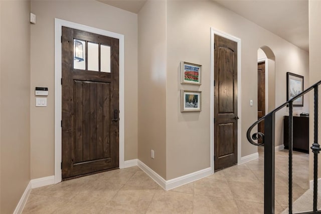 entrance foyer with light tile patterned floors, arched walkways, and baseboards