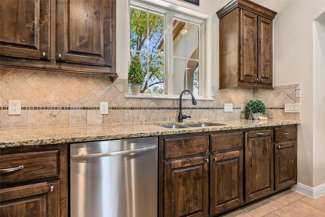 kitchen with stainless steel dishwasher, backsplash, a sink, and light stone countertops