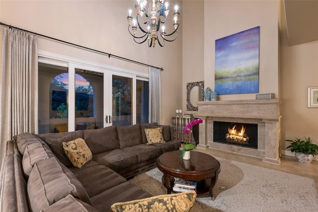 living room with a high ceiling, a chandelier, and a high end fireplace